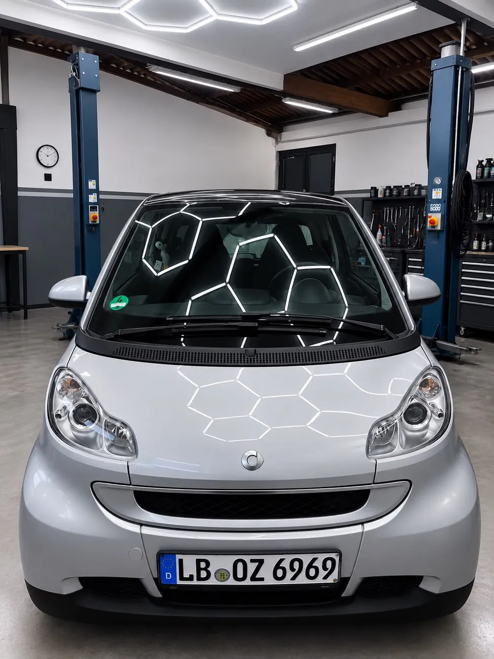 Silberner smart fortwo mit Hochglanz unter Hexagon-Beleuchtung im Studio